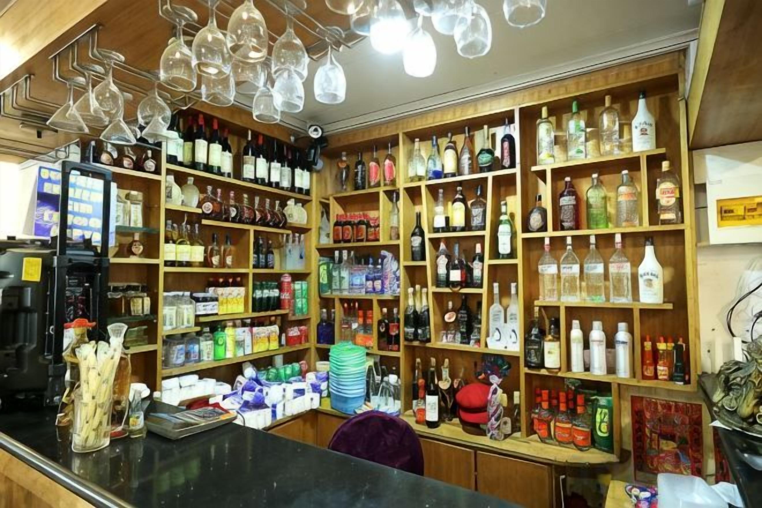 A bar area with shelves of bottles and glasses.