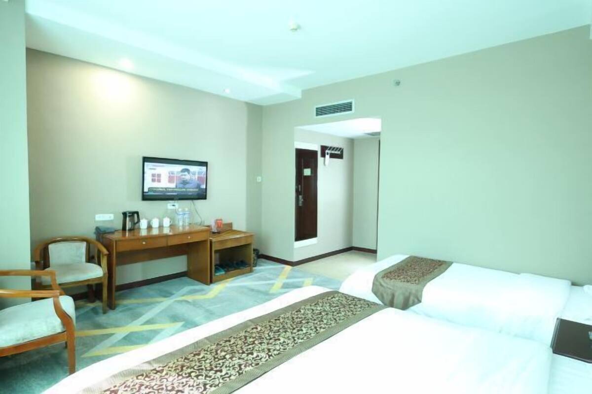 Une chambre d’hôtel avec un lit, un bureau et une chaise, une télévision et une porte.
