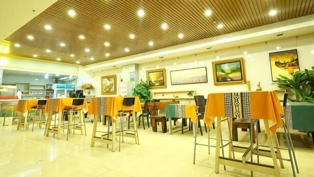 Un restaurante con techo de madera, mesas con manteles naranja y obras de arte enmarcadas en las paredes.