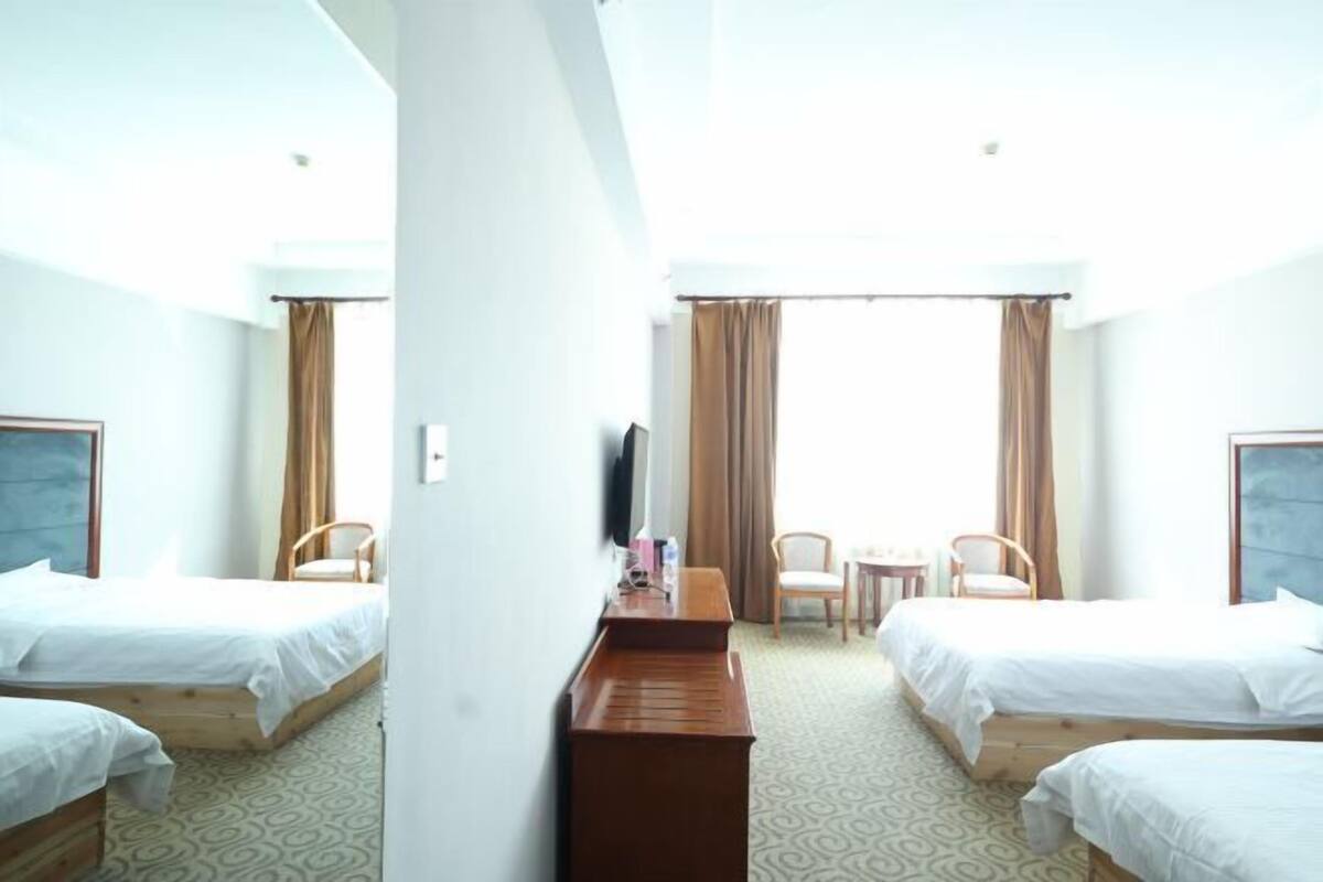Une chambre d’hôtel avec deux lits, un bureau, une chaise et un téléviseur.