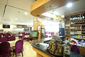 Un interior de restaurante con mesas, sillas, una barra y una exhibición de bebidas.