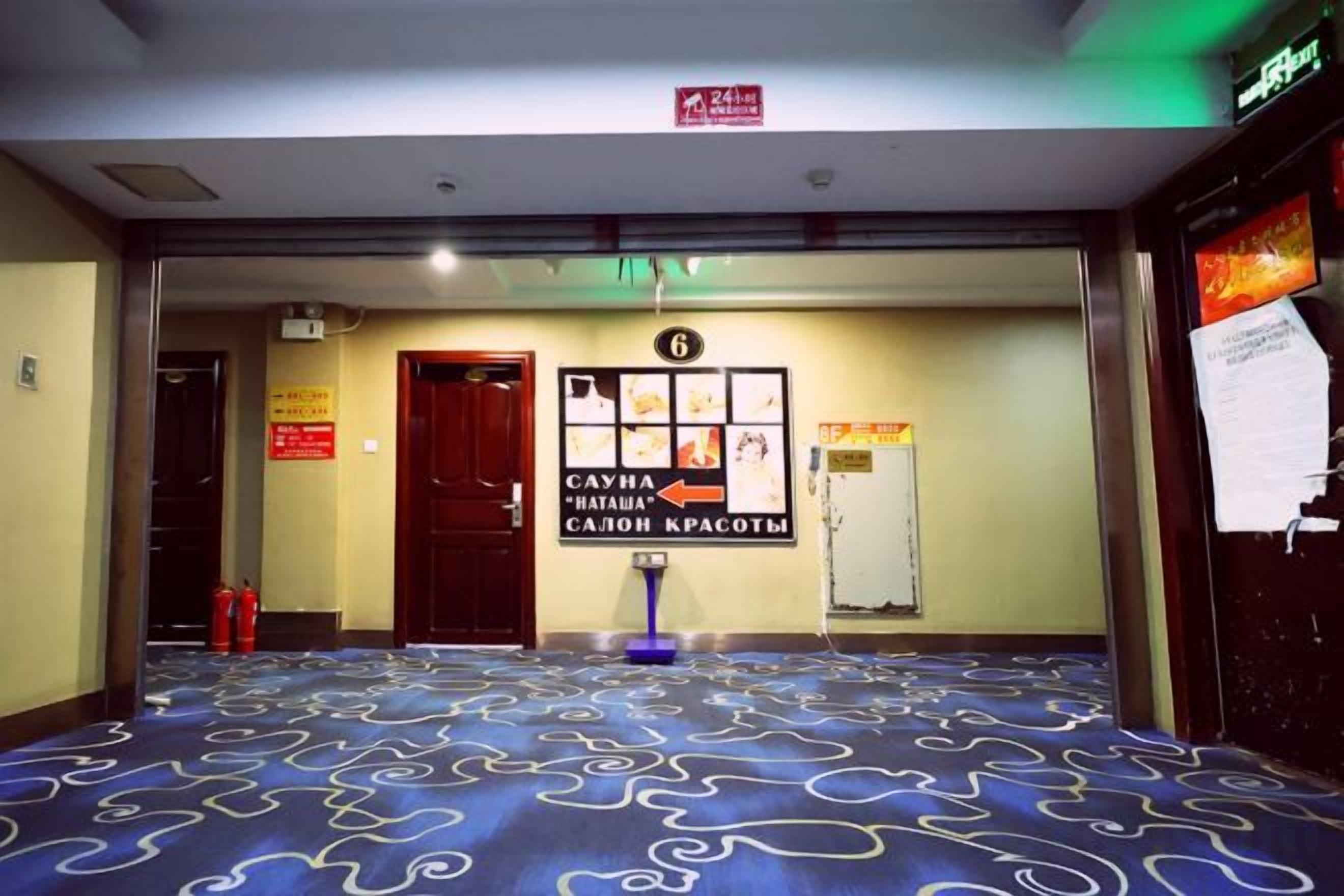 A hotel lobby with a patterned carpet, a reception desk, and a sign indicating room number 6.