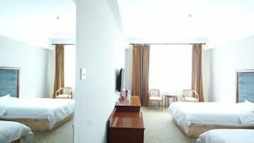 A hotel room with two single beds, a desk, a chair, a TV, and a window with curtains.