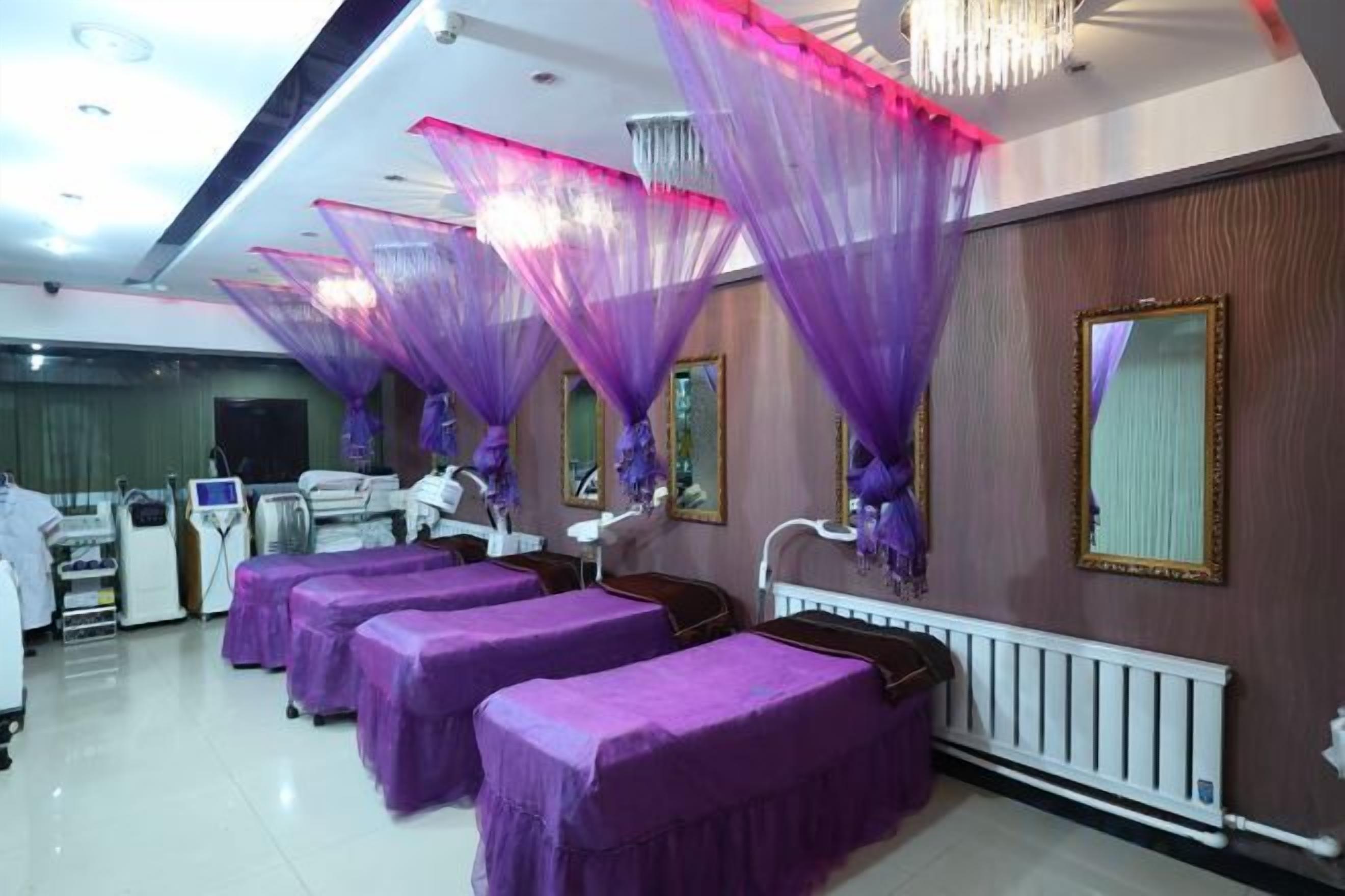 A room with beds covered in purple, a white radiator, and a mirror on the wall.