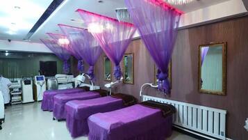 A room with beds covered in purple, a white radiator, and a mirror on the wall.