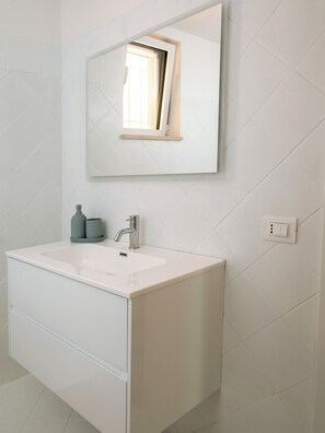 Une salle de bain avec un meuble-lavabo blanc, un miroir et un robinet.