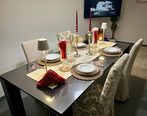 Une table à manger dressée avec des assiettes, des verres et des couverts, et un téléviseur fixé au mur en arrière-plan.