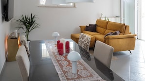A modern living room with a sofa, a dining table with candles, and pendant lights.