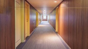 A long, narrow hallway with wooden paneling on the walls and carpeted floor. - Hotel Koyo Annex (Hashima)