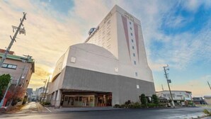 A modern hotel with a prominent curved facade, a flat roof, and a large entrance area.