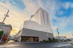 Un hotel moderno con una fachada curva destacada, un techo plano y un amplio espacio de entrada.