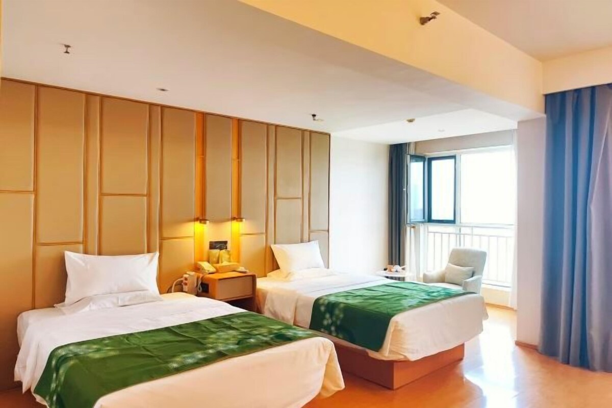 A hotel room with two beds, a balcony, and a view of the outdoors.