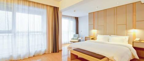 A modern hotel room with a large bed, a bedside table, a chair, and a large window with curtains.