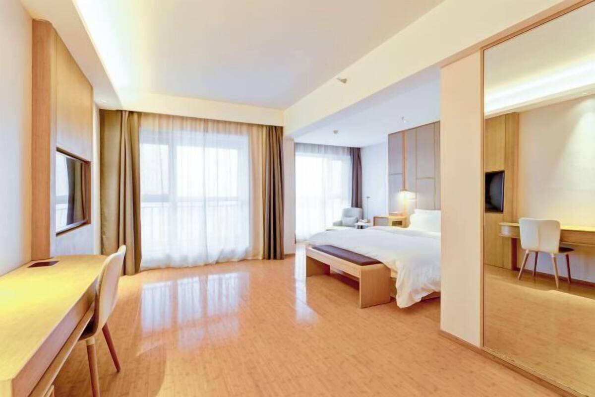 Ein Hotelzimmer mit Bett, Nachttisch, Lampe und einem großen Spiegel.