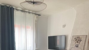 Un salon moderne doté d’un téléviseur à écran plat, d’une cheminée et d’une grande fenêtre agrémentée de rideaux.