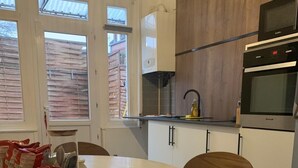 Une cuisine moderne avec des meubles blancs, une table de salle à manger ronde et un plancher en bois.