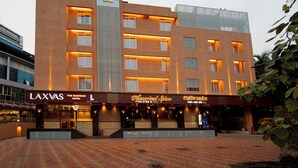 Un hotel con un cartel llamativo que indica 'LAXVAS THE BUSINESS HOTEL' y un restaurante 'FINE DINING & SPAZE'.