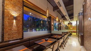 Un restaurante con paredes de ladrillo, bancos de madera y lámparas colgantes.