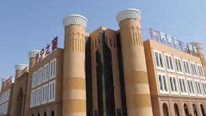 A hotel with a distinctive architectural style featuring cylindrical towers and a central vertical structure. - Ayile Holiday Hotel (Yining City)