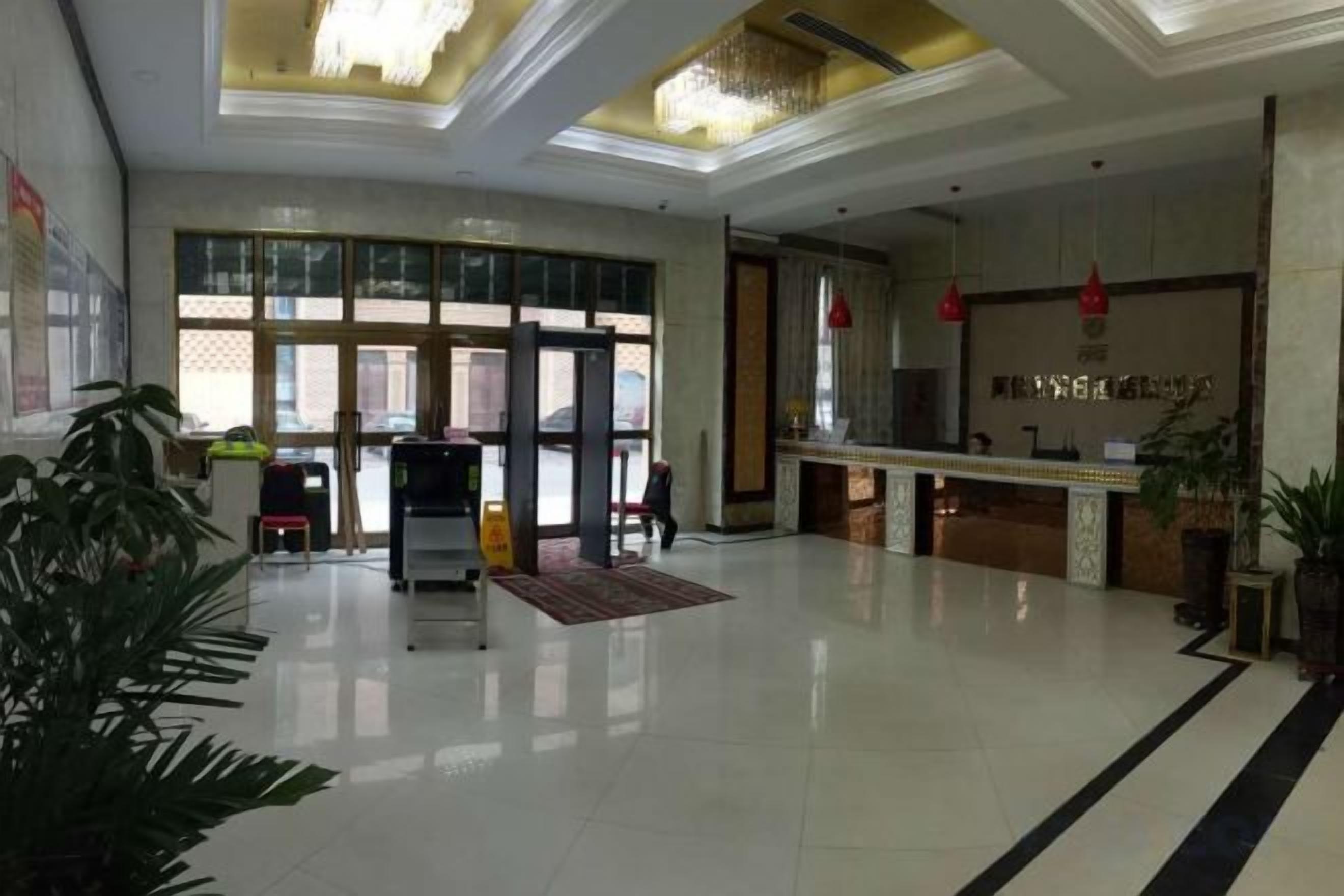 A hotel lobby with a reception desk, a turnstile, and a large window.