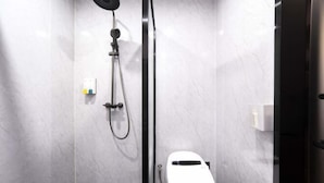 A modern bathroom with a shower, toilet, and a marble wall. - Ayile Holiday Hotel (Yining City)