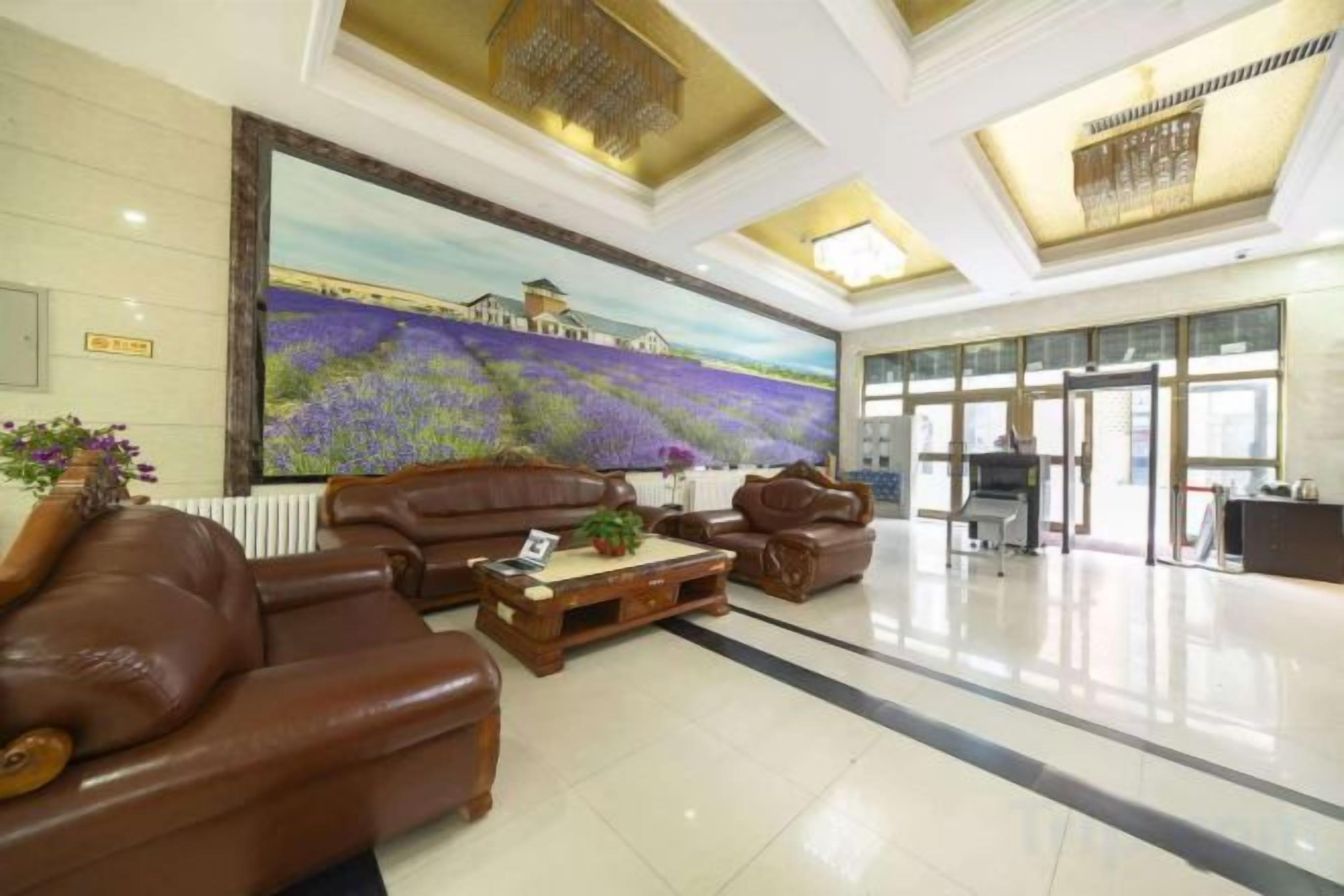 A lobby with leather sofas, a large painting, and a reception desk.