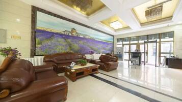 A lobby with leather sofas, a large painting, and a reception desk.