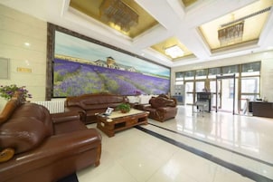 A lobby with leather sofas, a large painting, and a reception desk.