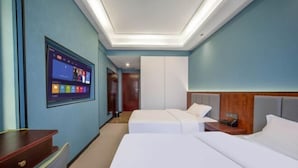 A hotel room with two beds, a desk, a TV mounted on the wall, and a ceiling light. - Ayile Holiday Hotel (Yining City)