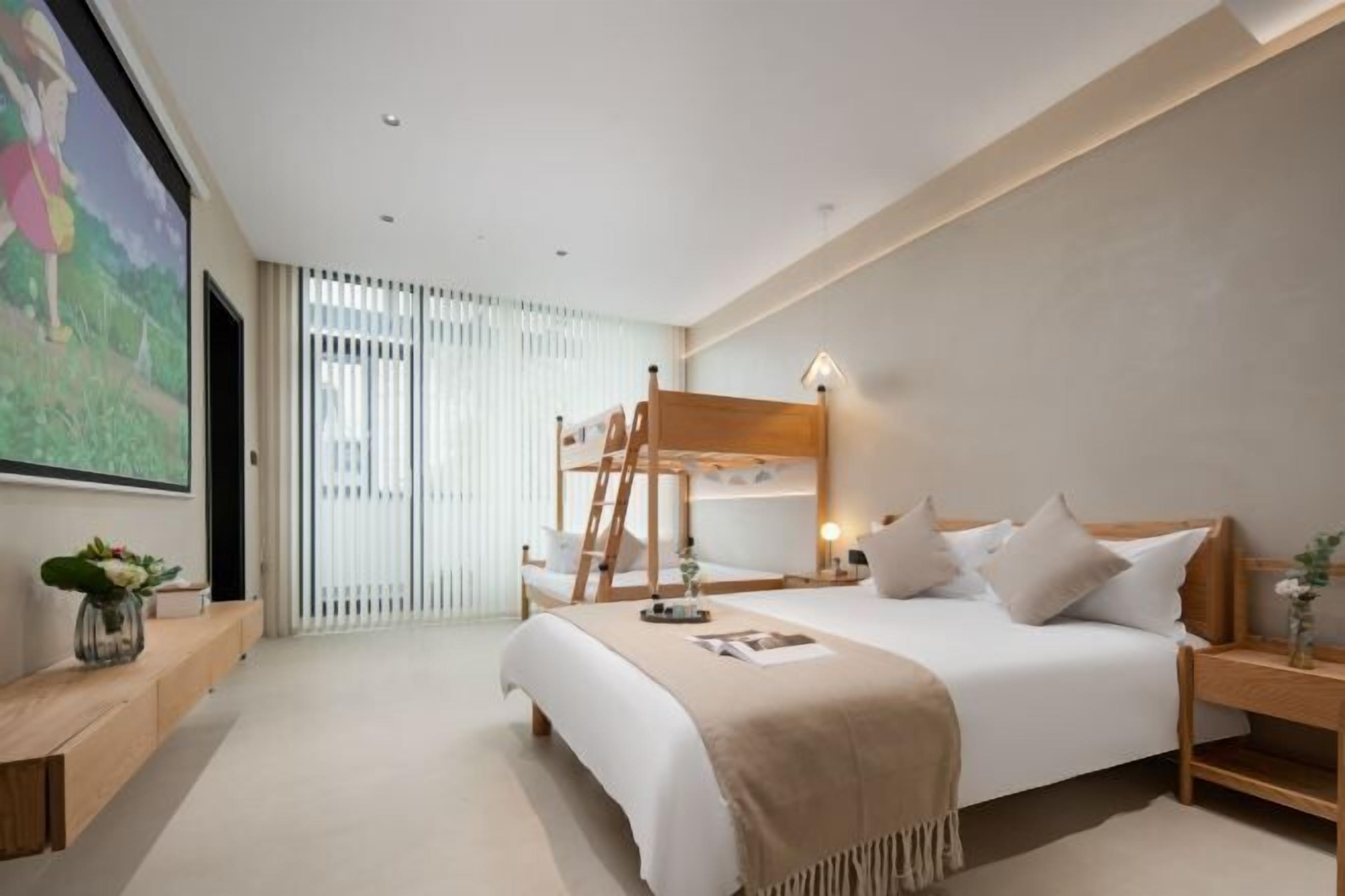 Une chambre moderne avec un lit superposé, une table de chevet avec une lampe, une grande fenêtre avec des stores et un tableau au mur.