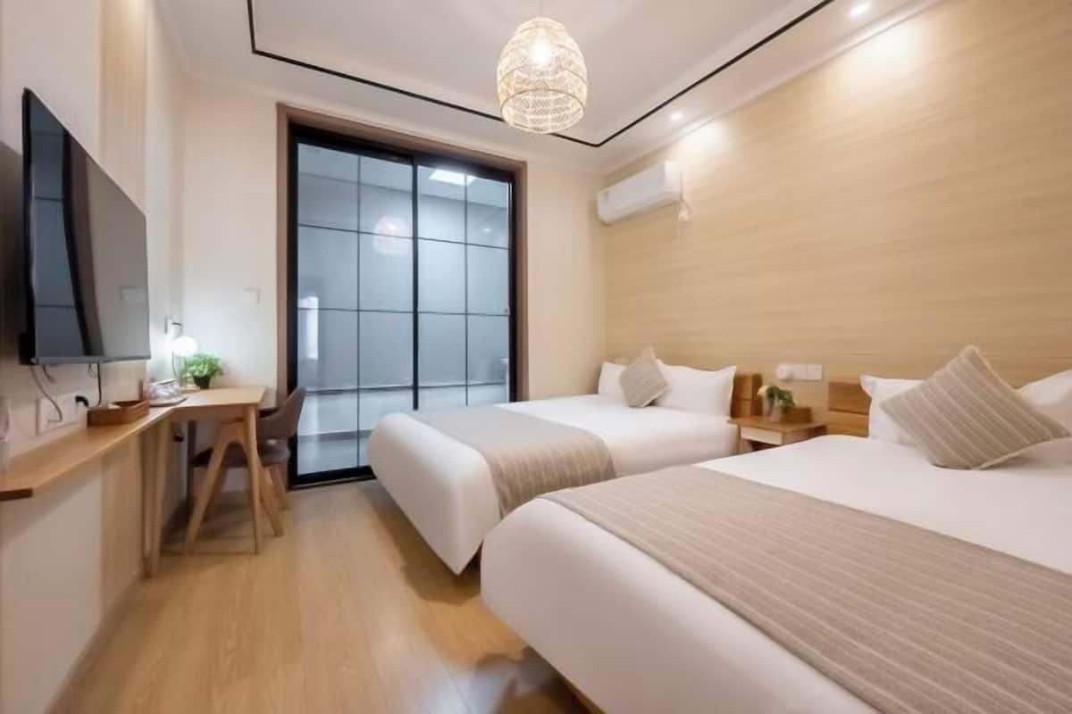 Una habitación de hotel con dos camas, un escritorio, un televisor y un ventanal grande.