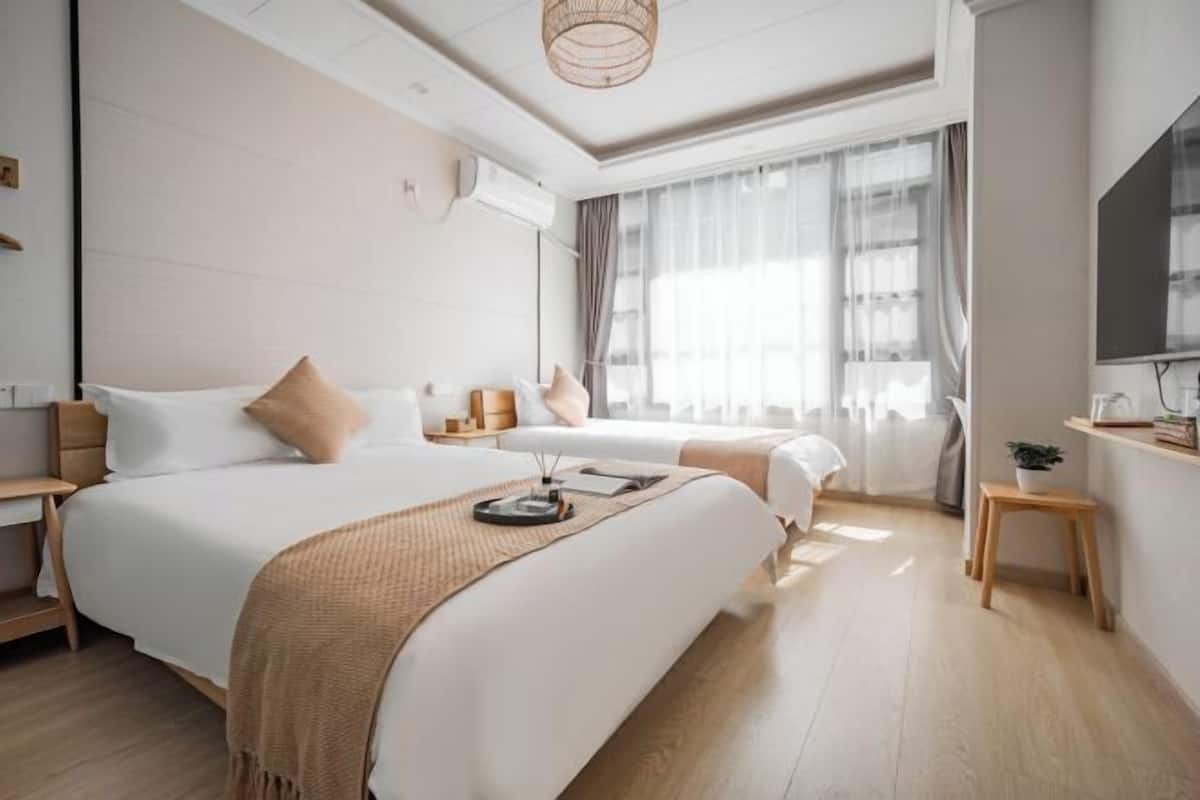 Una habitación de hotel moderna con una cama grande, mesitas de noche, un televisor y una ventana con cortinas.