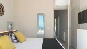 Een slaapkamer met een bed, een spiegel, een televisietoestel en uitzicht op buiten.