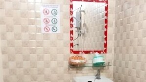 Een kleine badkamer met toilet, wastafel en spiegel. De wanden en vloer zijn betegeld.