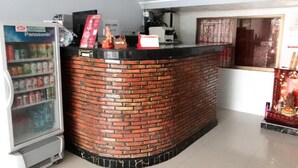 Een receptiezone met een metselwerk toonbank, een Panasonic koelkast, en een raam met decoraties.