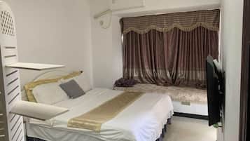 A bedroom with a bed, a TV, and a window with curtains.
