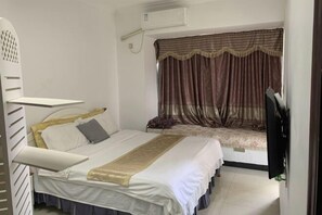 Un dormitorio con cama, televisor y ventana con cortinas.