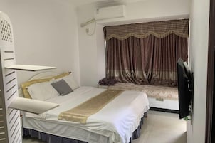 Un dormitorio con cama, televisor y ventana con cortinas.