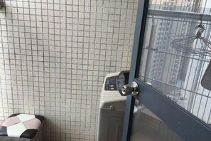 A room with a tiled wall, a washing machine, and a door with a view of buildings. - Enping Jinjiang International New Town Apartment (Enping)