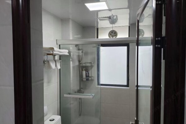Un baño moderno con cabina de ducha de vidrio, inodoro y perchero para toallas.