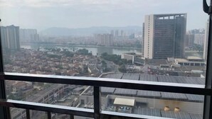 Un edificio alto con vistas a un paisaje urbano, que incluye zonas residenciales y un río.