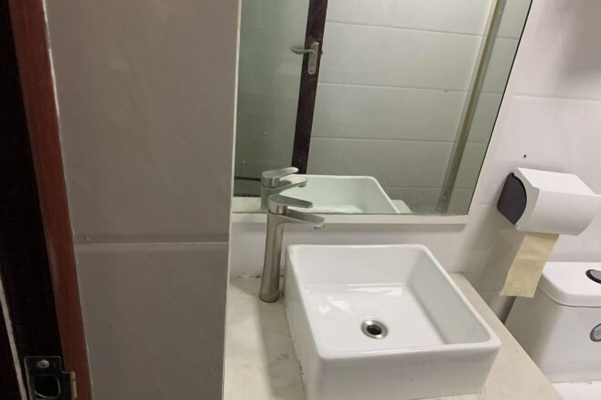 Un baño con lavamanos blanco, un espejo y un inodoro.