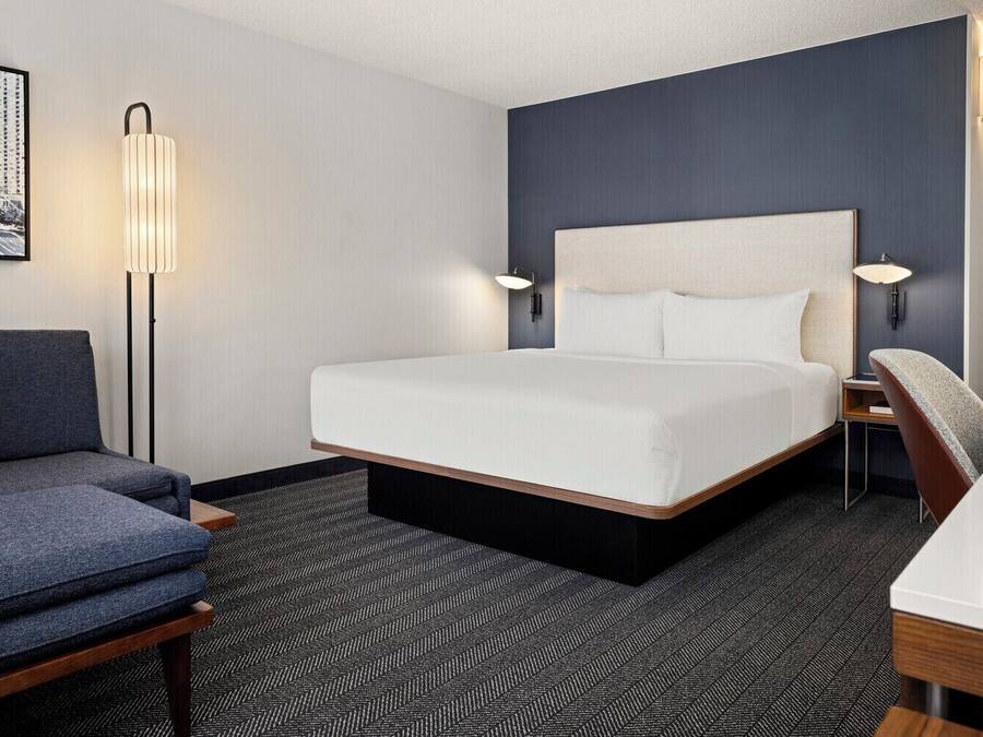 Una habitación de hotel con una cama grande, un sofá, un escritorio y una silla.