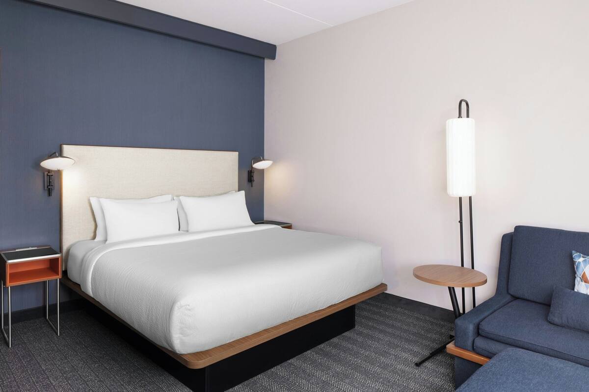 Una habitación de hotel con una cama grande, mesitas de noche, una pequeña mesa redonda y un sofá.