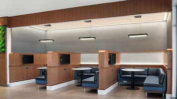 Ein modernes Interieur mit Sitzbereichen, Tischen und Einbauleuchten.