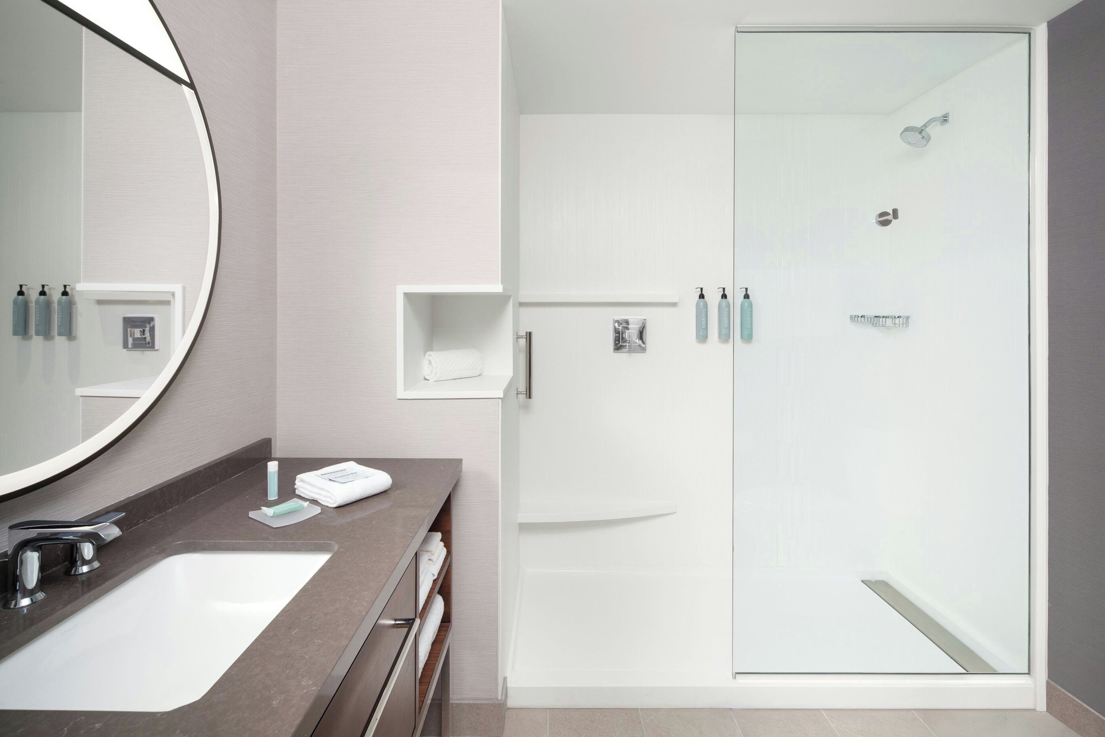 A modern bathroom with a large sink, a mirror, and a glass-enclosed shower.