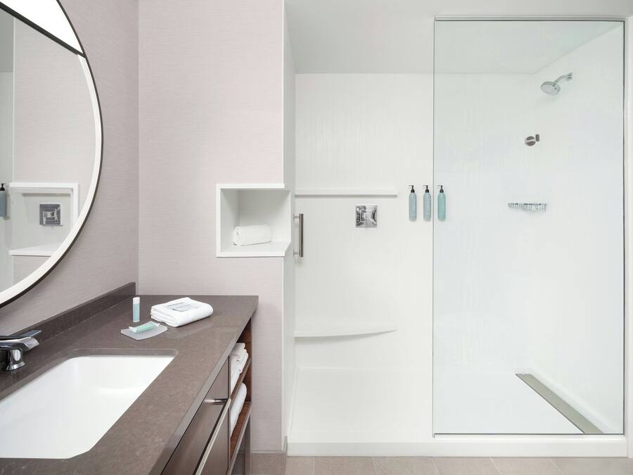 Un bany modern amb un lavabo gran, un mirall i una dutxa amb envàs de vidre.