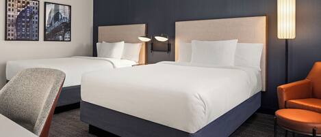 Habitación de hotel con dos camas, una silla y una lámpara.