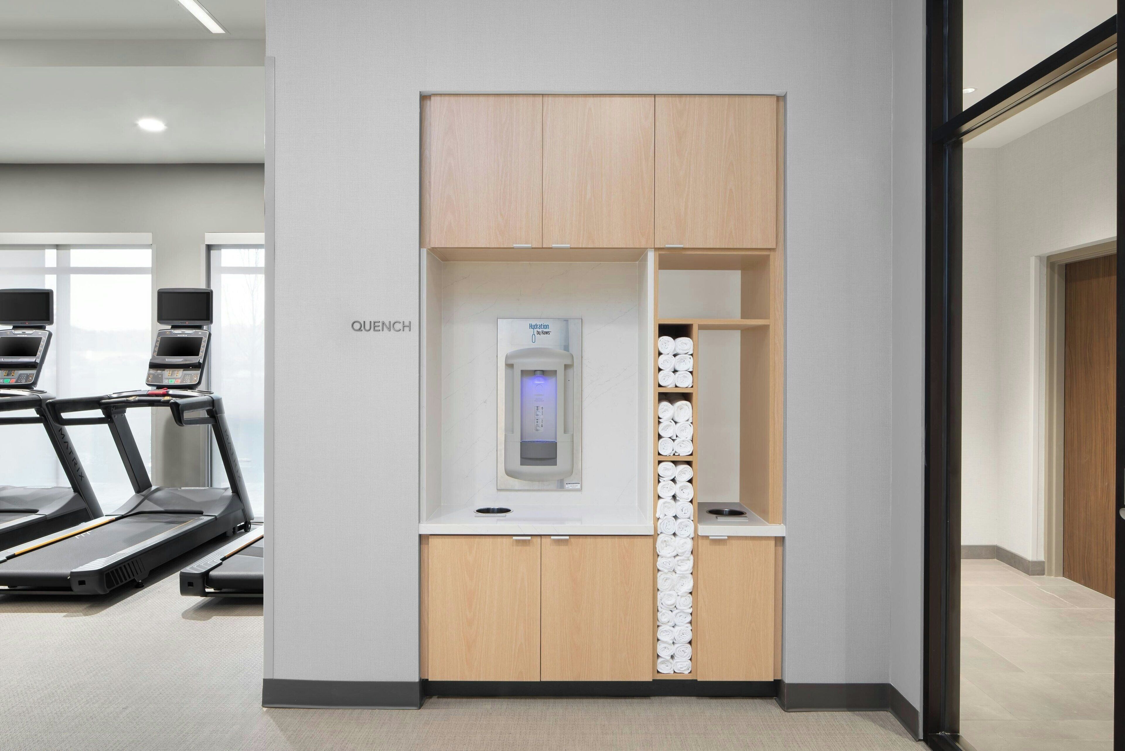 A fitness area with treadmills, a water dispenser, and neatly arranged towels.