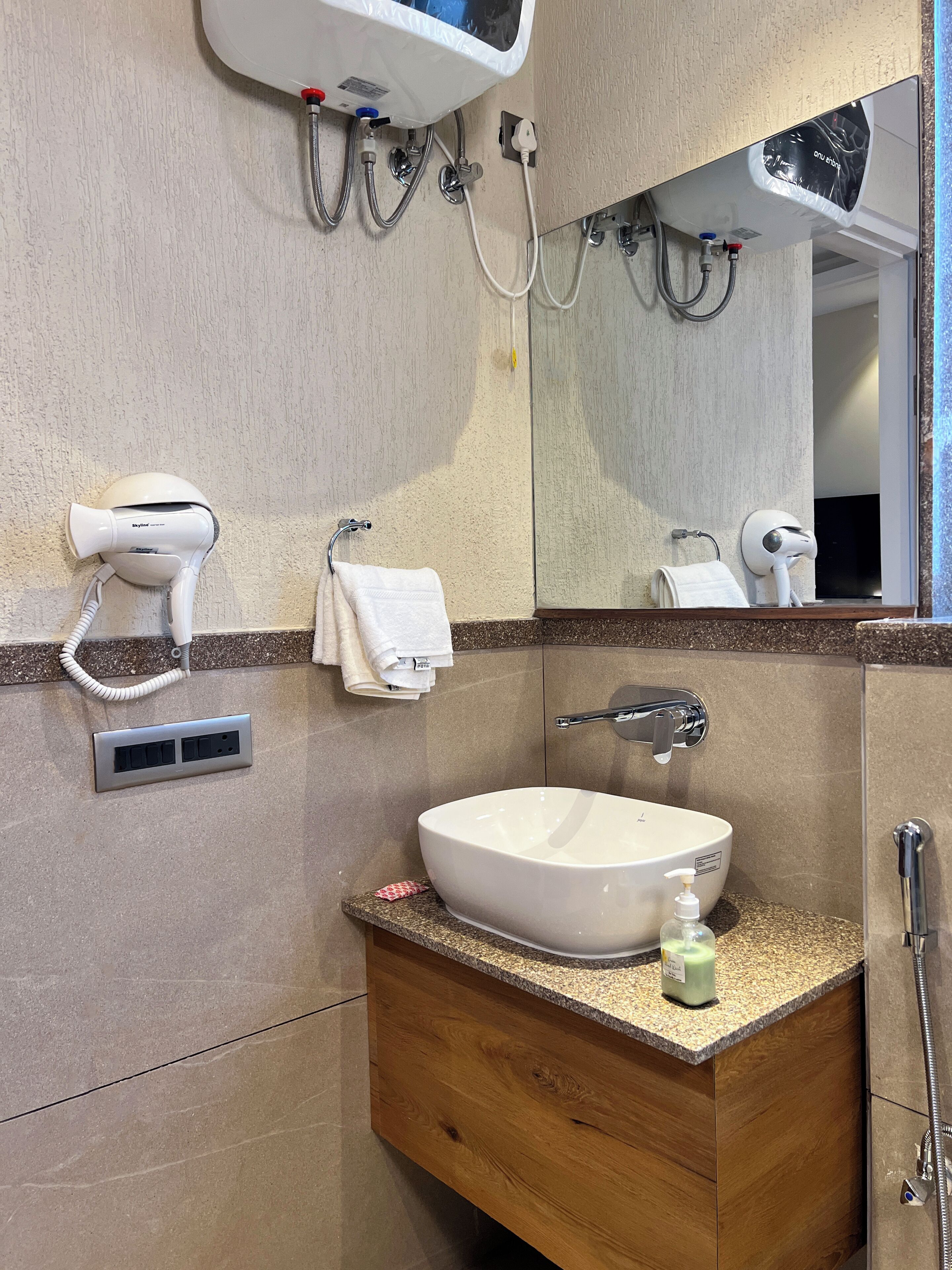 A bathroom with a sink, mirror, towel rack, hairdryer, and shower.